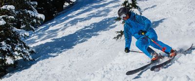 A skier in a blue jacket and pants skis down a freshly groomed ski slope.  

 