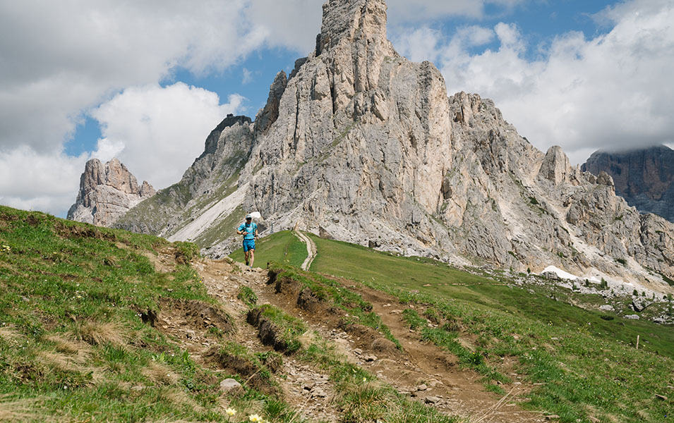 A trail runner wearing a blue shirt makes his way down a rocky trail during the UTMB race.