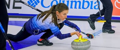Woman pushing a Curling stone down the curling sheet. 