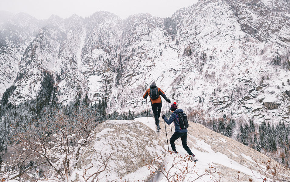 Two people hiking up a snow trail. 