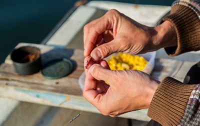  A person deftly baits a fishing hook with a worm.