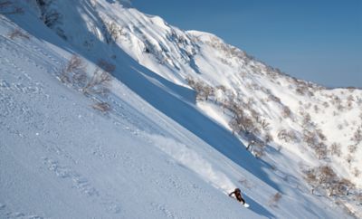 Keisuke snowboarding on a bluebird day.