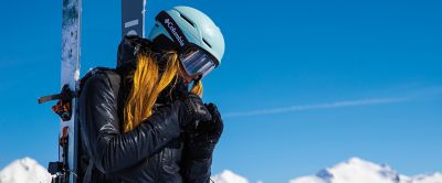 A woman at the top of a mountain with ski gear.
