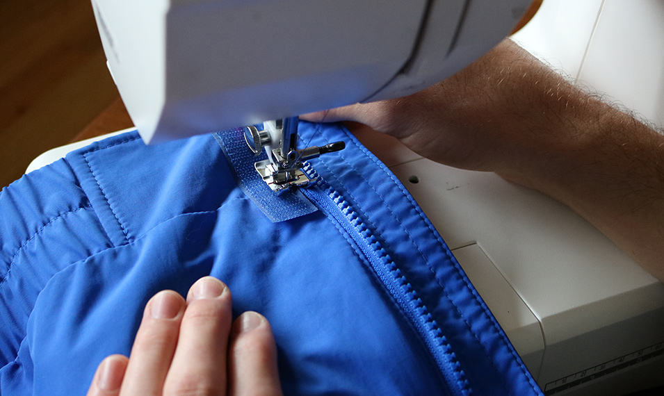 Closeup of a jacket being sewn on a sewing maching. 