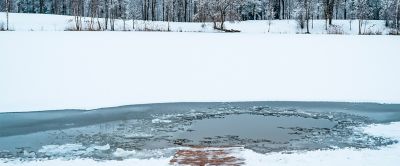A wooden dock extends into an icy pool of water that looks ideal for cold plunging. 