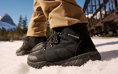 Close up of black Columbia Sportswear winter boots walking across a snowy meadow. 