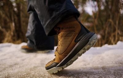 Close up of brown Columbia winter boots walking across ice, showing the traction lugs of the boot. 