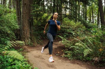 A woman running down a wooded trail.