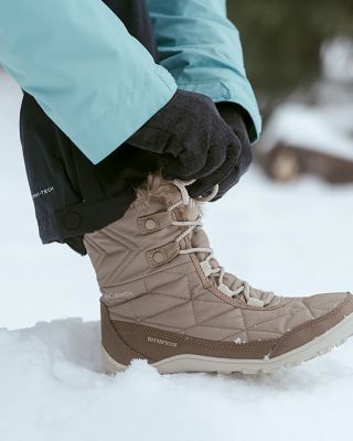A zoomed-in shot of a person's feet in winter boots walking through the snow.