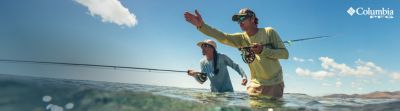 Man and Woman wearing PFG fishing in waist-deep water.