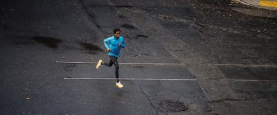 A runner in tights and a sun-protective long sleeve top focuses on his form as he powers through a training session.