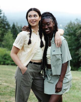 Two women standing in a green outdoor landscape.