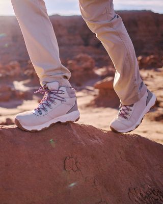 Closeup of someone walking with tan hiking boots on a rock.