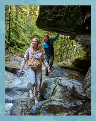 Two hikers wearing rain jackets in a forest.