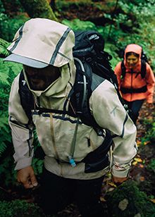 A couple in rain gear in the woods.
