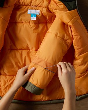 Close-up of someone snipping the seam of their Outgrown jacket.