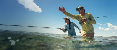 A couple waist deep in water fishing.