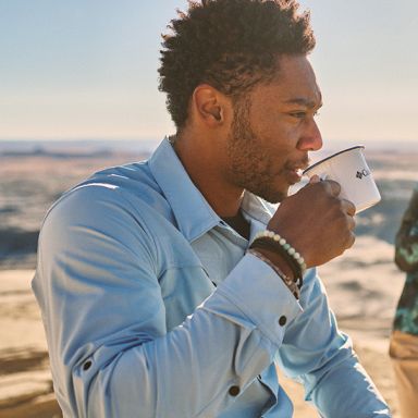 Man sipping coffee on a trail.