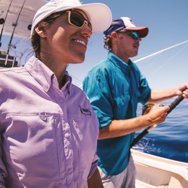 Anglers on a boat reeling in a fish.