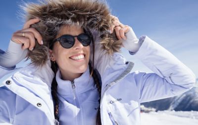 A woman wearing sunglasses pulls up the hood on her warm Columbia winter jacket.