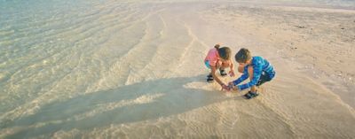 Two kids playing in the sand on a beach.