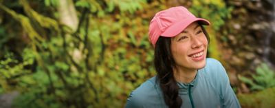 A woman on a hike wearing a Columbia ball cap.