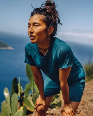 A woman wearing in sun protection gear hiking in the desert.