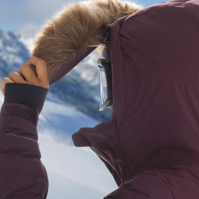 Close-up of model removing the optional fur on their hood.