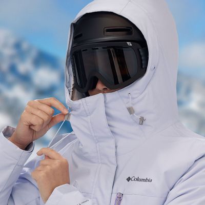 Skier tightening the drawcord on their hood fitting over their goggles and helmet.