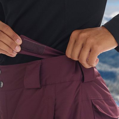 Close-up of a woman adjusting the tabs on the ski pants.