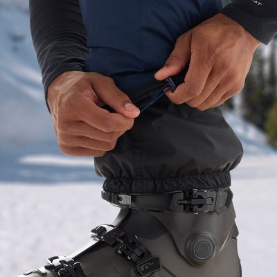 Close-up of model adjusting toggle on cuffs and internal gaiter over boot.