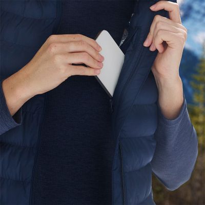 Model placing a phone into the chest zip pocket.
