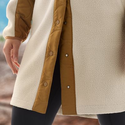 Close-up of model wearing a fleece jacket with a droptail hem.