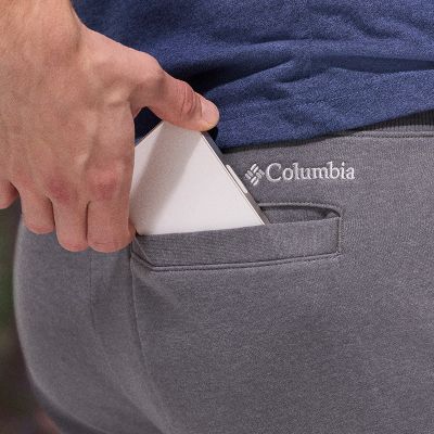 Close up shot of a model placing a phone into their back pocket.