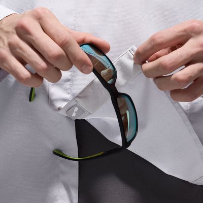 Close-up of a model cleaning their sunglasses with the inside fabric of the shirt.