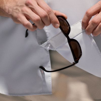 Close-up of a model wiping their sunglasses on the cleaning patch of their shirt.
