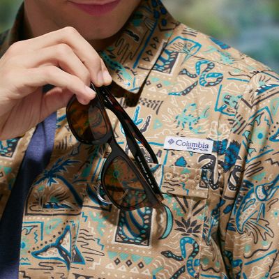 Close-up shot of a model placing sunglasses into their chest pocket.