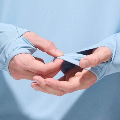 Model pulling the extended sleeves and thumbholes over their wrist.