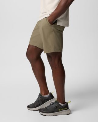 Waist-down image of a man wearing dark green shorts and sneakers.