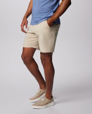 Waist-down image of a man wearing tan shorts and slip-on shoes.