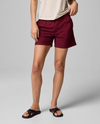 Waist-down image of a woman wearing maroon shorts and sandals.