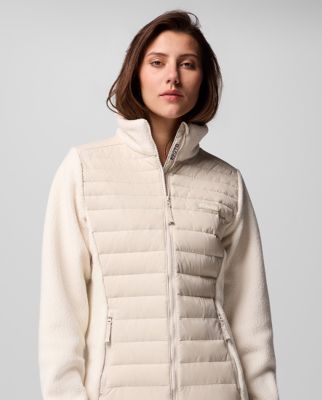 A woman wearing a cream-colored insulated jacket.