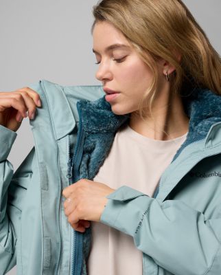 A woman opening her blue Interchange jacket to reveal the detachable inner layer.