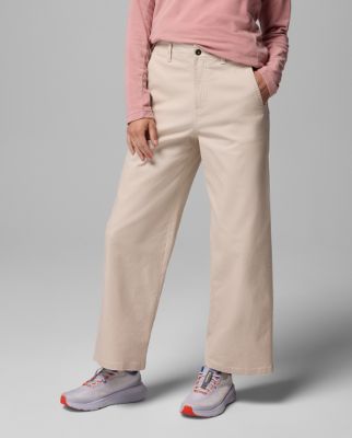 Waist-down image of a woman wearing white pants and sneakers.