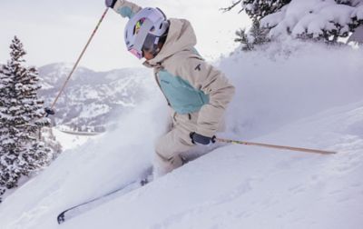 Poised on a steep slope of fresh powder snow, a skier plants a pole in anticipation of the next turn.