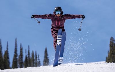 A skier in a one-piece Columbia Sportswear snow suit gracefully lands a big jump.