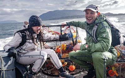 Two people, a man and a woman, are wearing Columbia Titanium waterproof jackets and pants as they head out on a boat for a day of fishing.