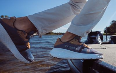 A person jumps onto a boat while wearing a pair of grippy Columbia PFG water shoes. 