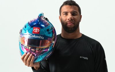 Bubba Wallace poses with his blue and red NASCAR helmet which sports a Columbia logo.