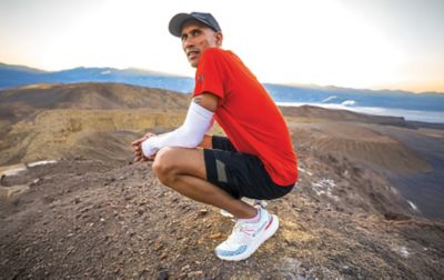  A runner, wearing a Columbia Sportswear running hat, running clothes and Konos running shoes, pauses to catch his breath and enjoy the view from a high ridgeline.
